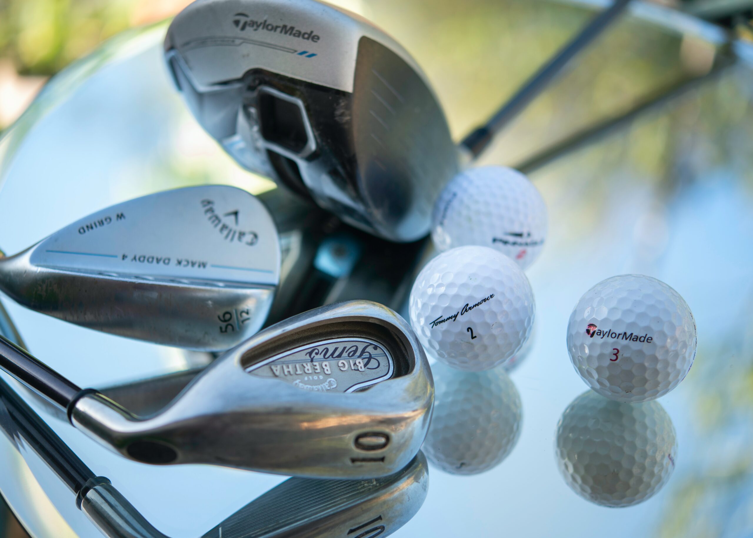 A close-up of two golf irons and a driver, along with three golf balls