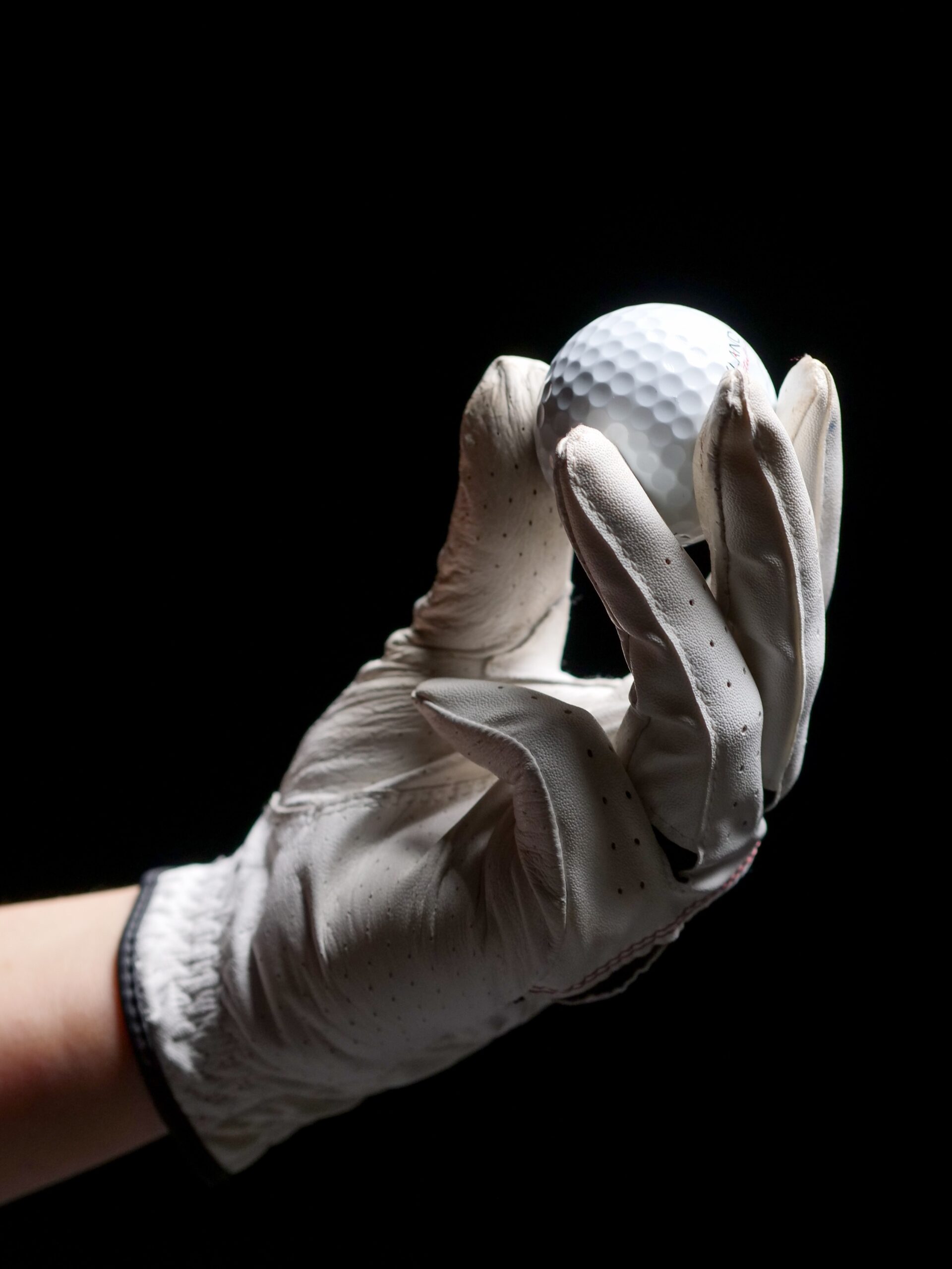 A gloved hand holding a golf ball.