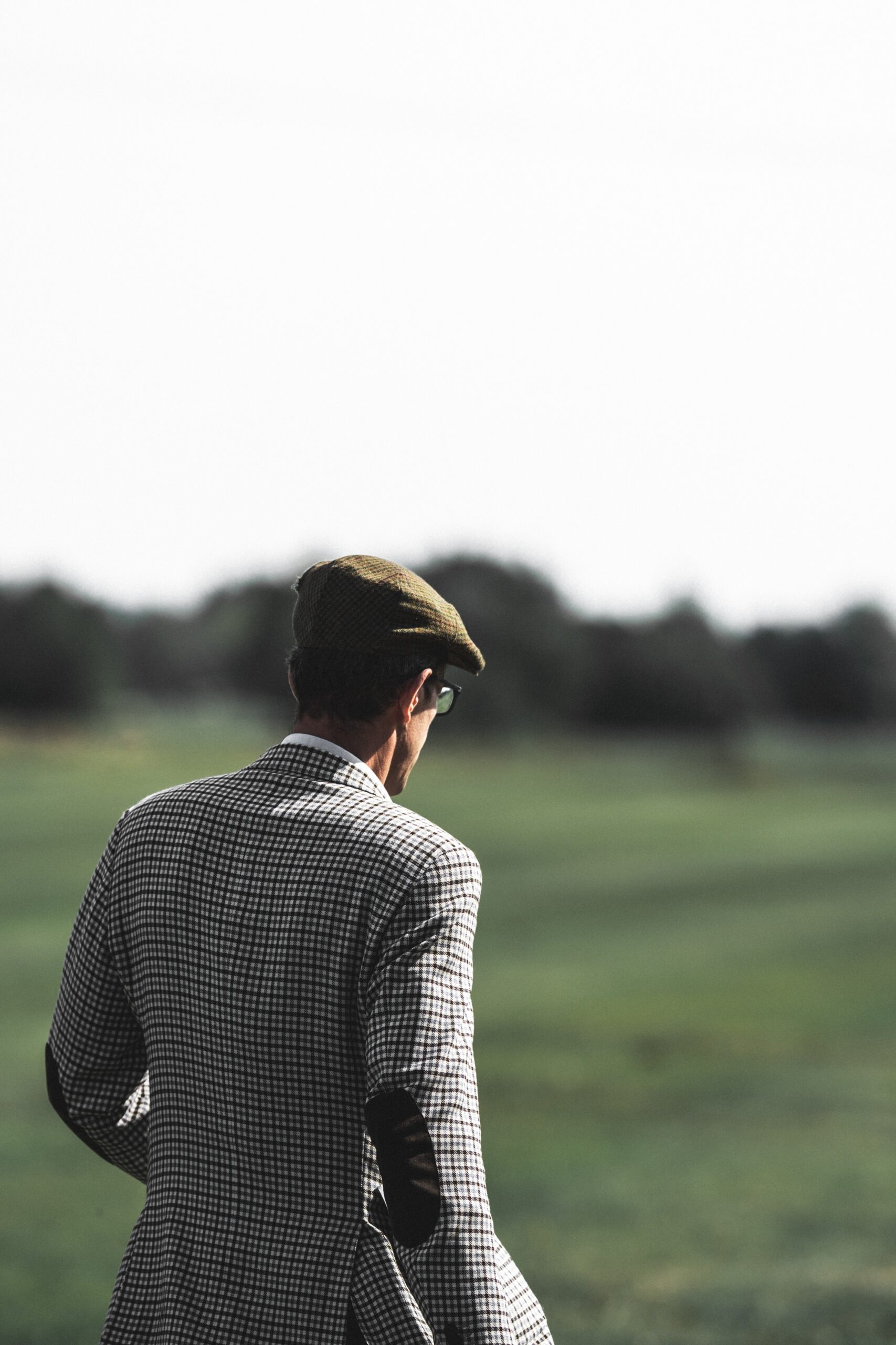 The back of a man dressed in old fashioned golfing attire.