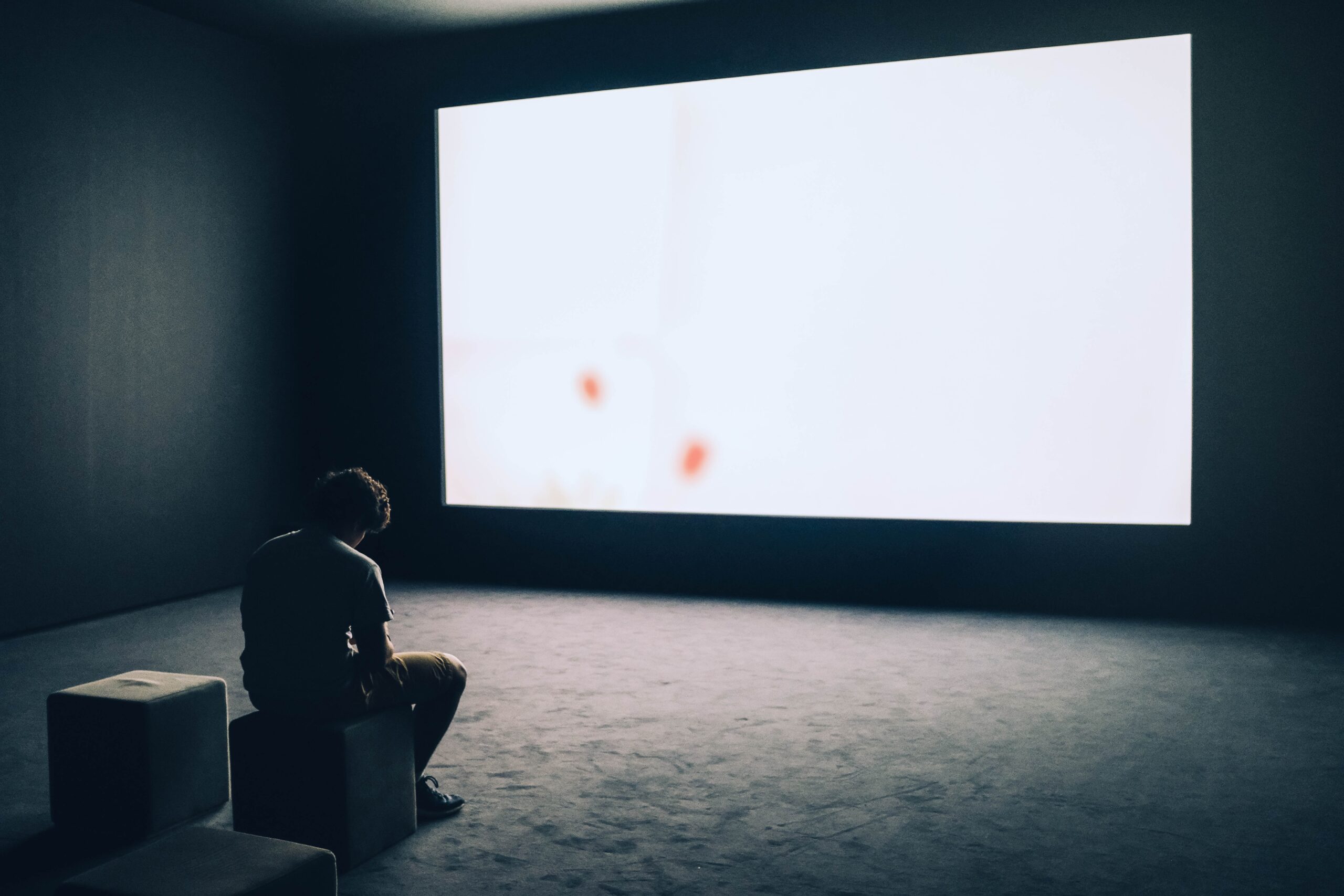 A man sitting in front of a projector screen.