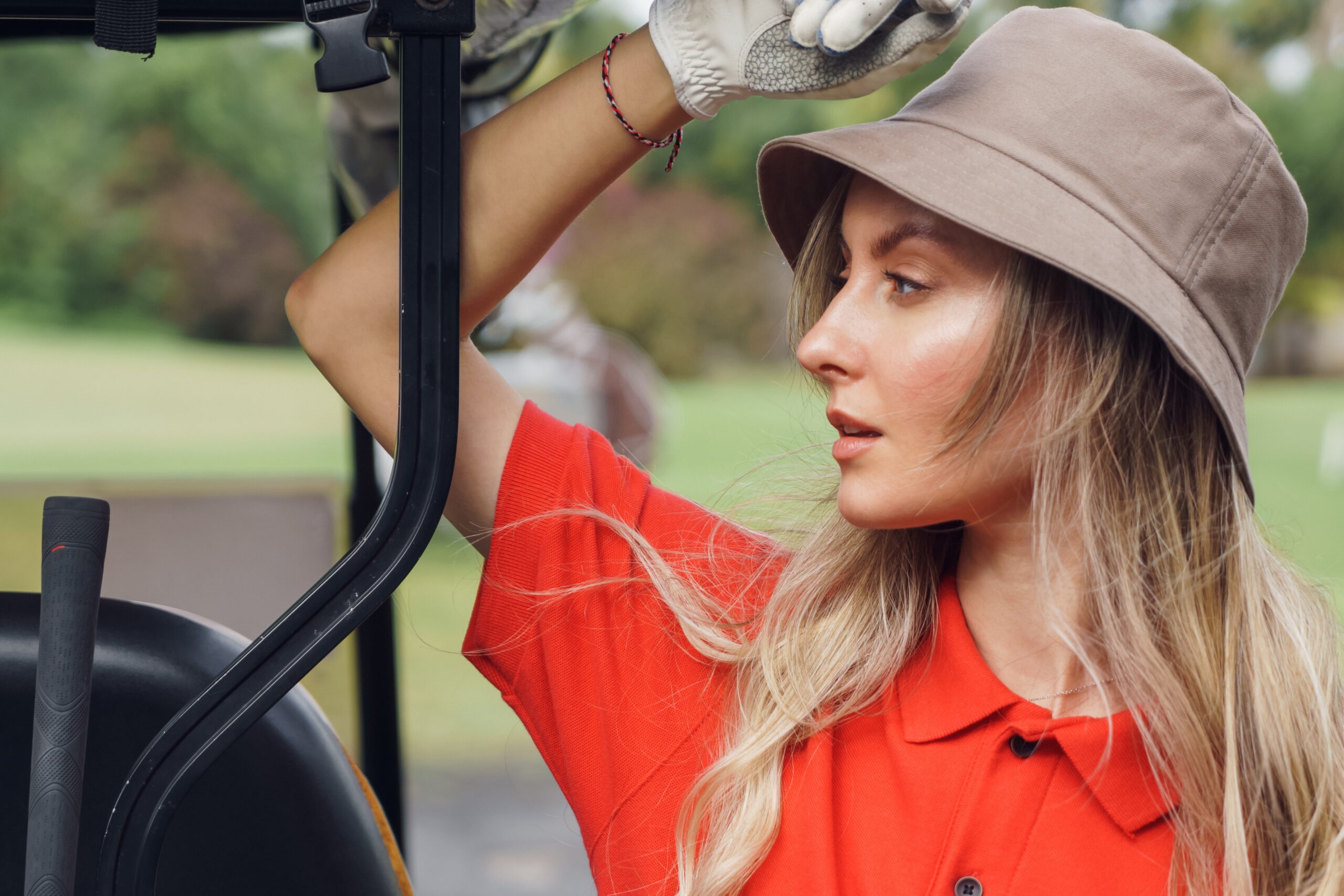 A golf cart girl leaning against a golf cart.