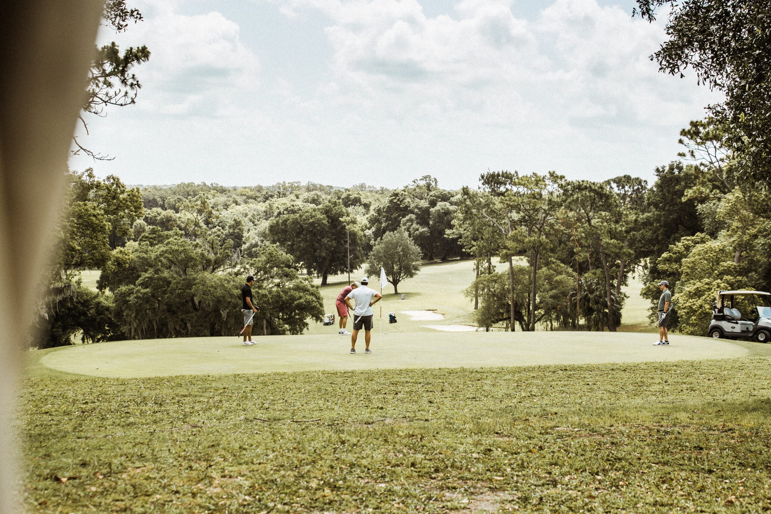 A distant view of four people standing on a golf putting green.