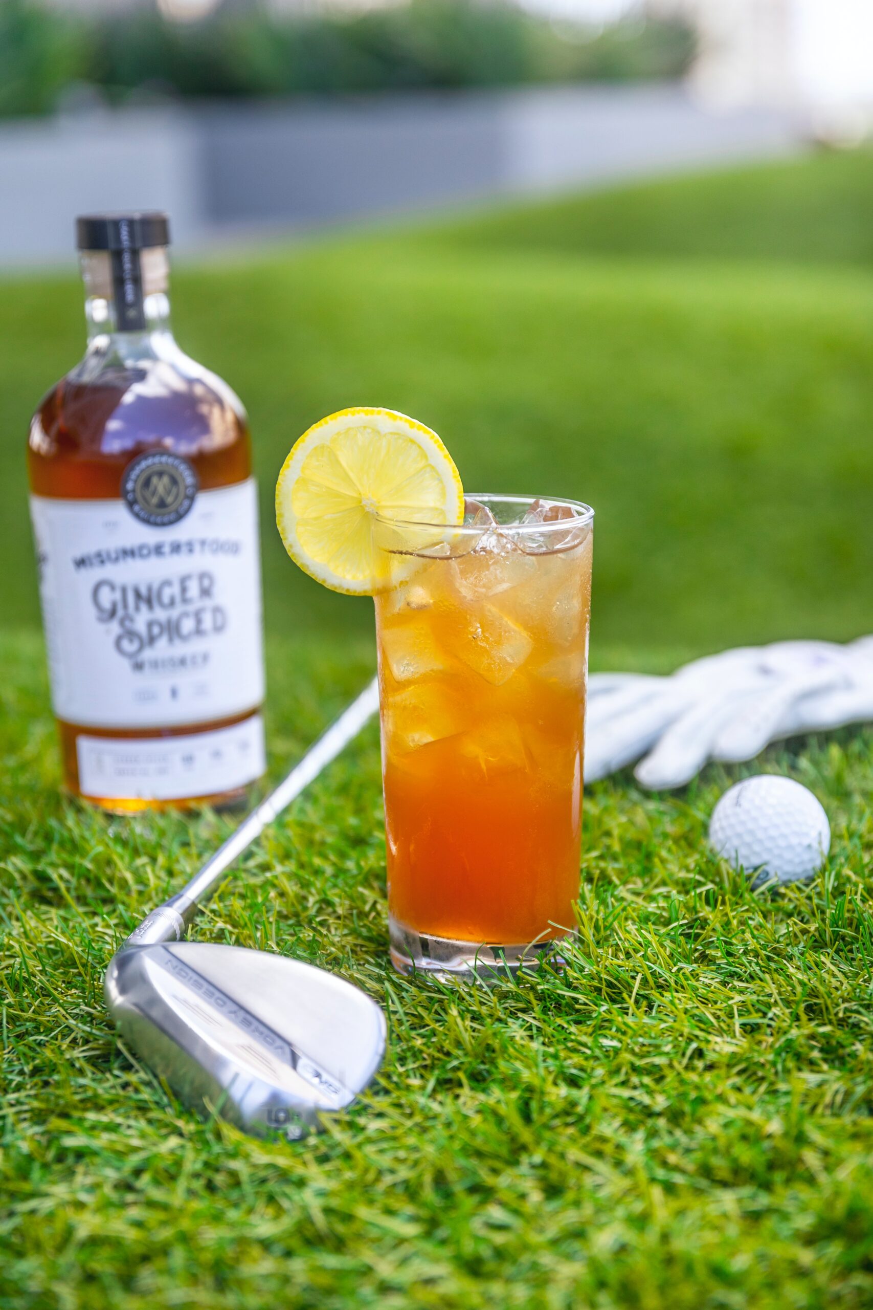 Cocktail resting on a bed of grass with a golf club and balls in the background