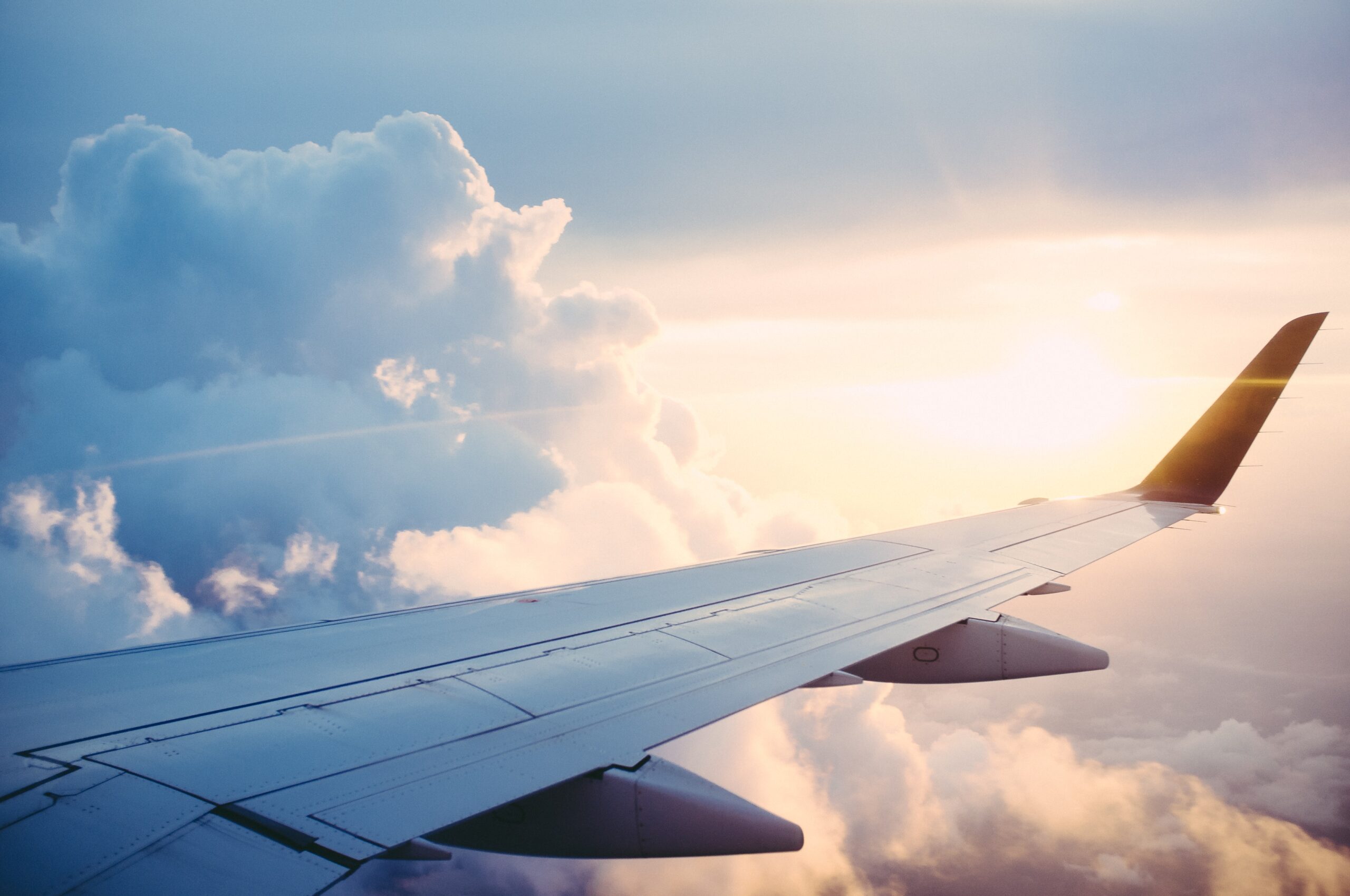 The wind of a plane with clouds in the background.